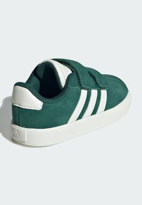 Sneaker in suede verde con dettagli in pelle bianca e tre strisce bianche. Presenta una chiusura a strappo e una soletta in gomma.