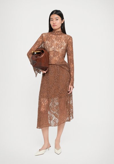 Robe en dentelle marron avec des manches longues et un col montant, assortie à un sac en cuir marron. Présente des motifs floraux et une jupe mi-longue.