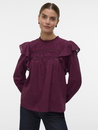 Blouse bordeaux avec des manches froncées, motif à pois texturé et taille cintrée. Présente un col rond et des accents transparents.