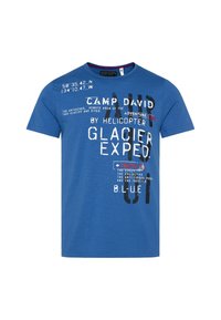 Camiseta de algodón azul con mangas cortas, cuello redondo, con texto impreso en blanco y negro, acentos rojos y elementos gráficos.