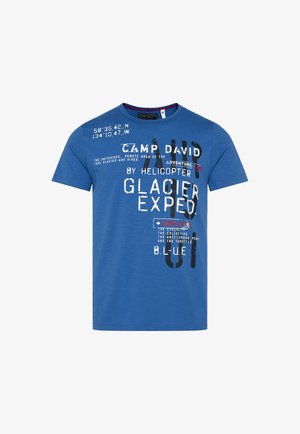 Maglietta in cotone blu con maniche corte, scollatura rotonda, caratterizzata da testo stampato in bianco e nero, con accenti rossi e elementi grafici.