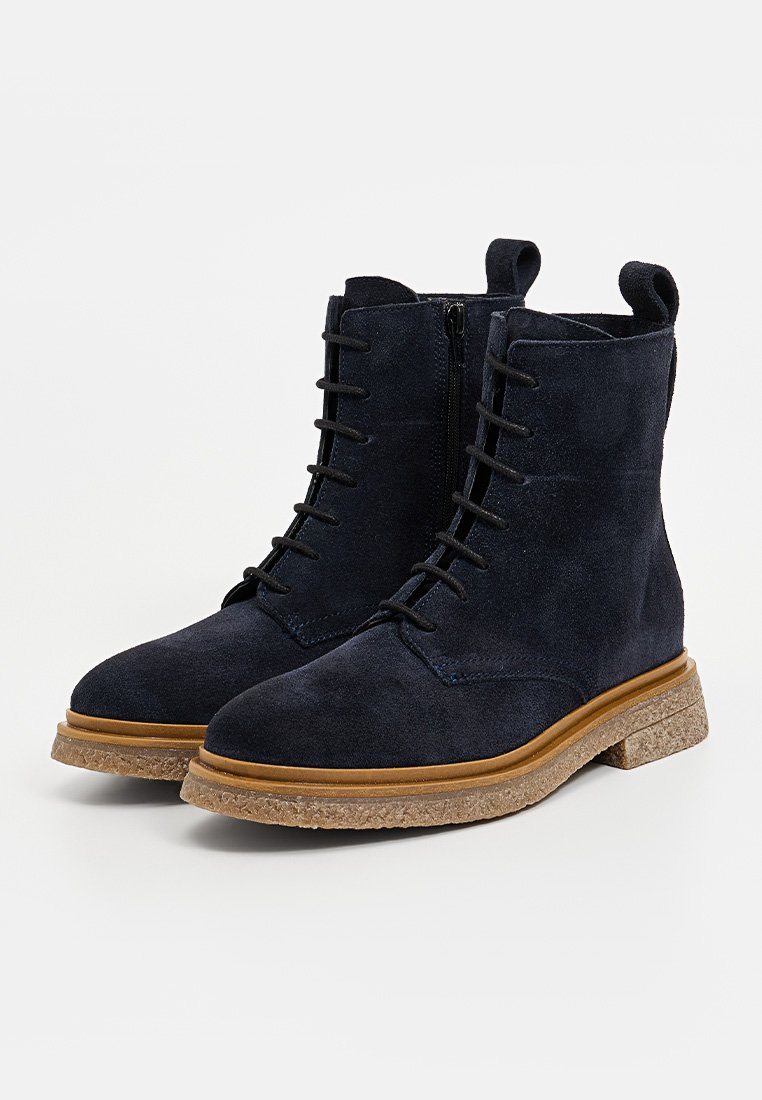 Navyblaue Wildleder-Stiefeletten mit runder Zehenpartie, Schnürung vorne, seitlichem Reißverschluss und einer strukturierten, tanfarbenen Gummisohle.