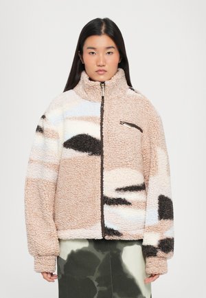 Fleece-takki vetoketjulla, jossa on beige, ruskea, musta ja vaaleansininen kuviokko. Pehmeä rakenne ja korkea kauluksen muotoilu.