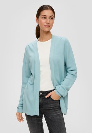 Cardigan bleu clair en tissu tricoté texturé, à l'avant ouvert, avec des poignets et un ourlet côtelés, porté sur un haut blanc et un jean noir.