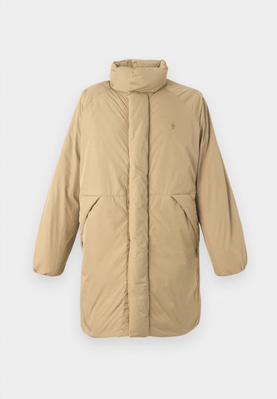 Beige gewatteerde jas met hoge kraag, lange mouwen, voorzakken en verticale stiksels. Bevat een subtiele logo op de borst.