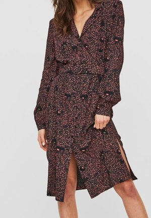 Vestido floral oscuro con mangas largas y diseño envolvente. Presenta una cintura ceñida con cinturón, un patrón de lunares y una abertura lateral en el dobladillo.