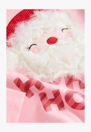 Lyserød stof med en broderet juleskikkelse, som har et tekstureret hvidt skæg, rød hat og trykt "HO HO HO" i farverne fra julestænger.