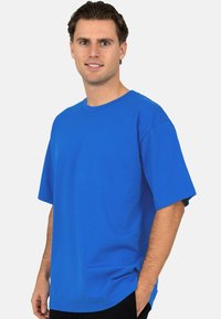 T-shirt bleu royal à manches courtes en coton, avec un col rond et une coupe décontractée, doté d'une texture lisse et uniforme.