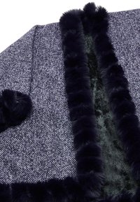 Strato esterno lavorato a maglia con un motivo texturizzato blu navy; foderato con morbido pelliccia sintetica nera e impreziosito da un bordino soffice blu navy lungo i bordi.