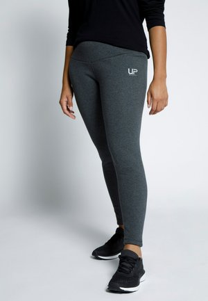 Graue Leggings mit hohem Bund und UP-Logo. Glatter Stoff, figurbetontes Design, kombiniert mit schwarzen Sportschuhen.