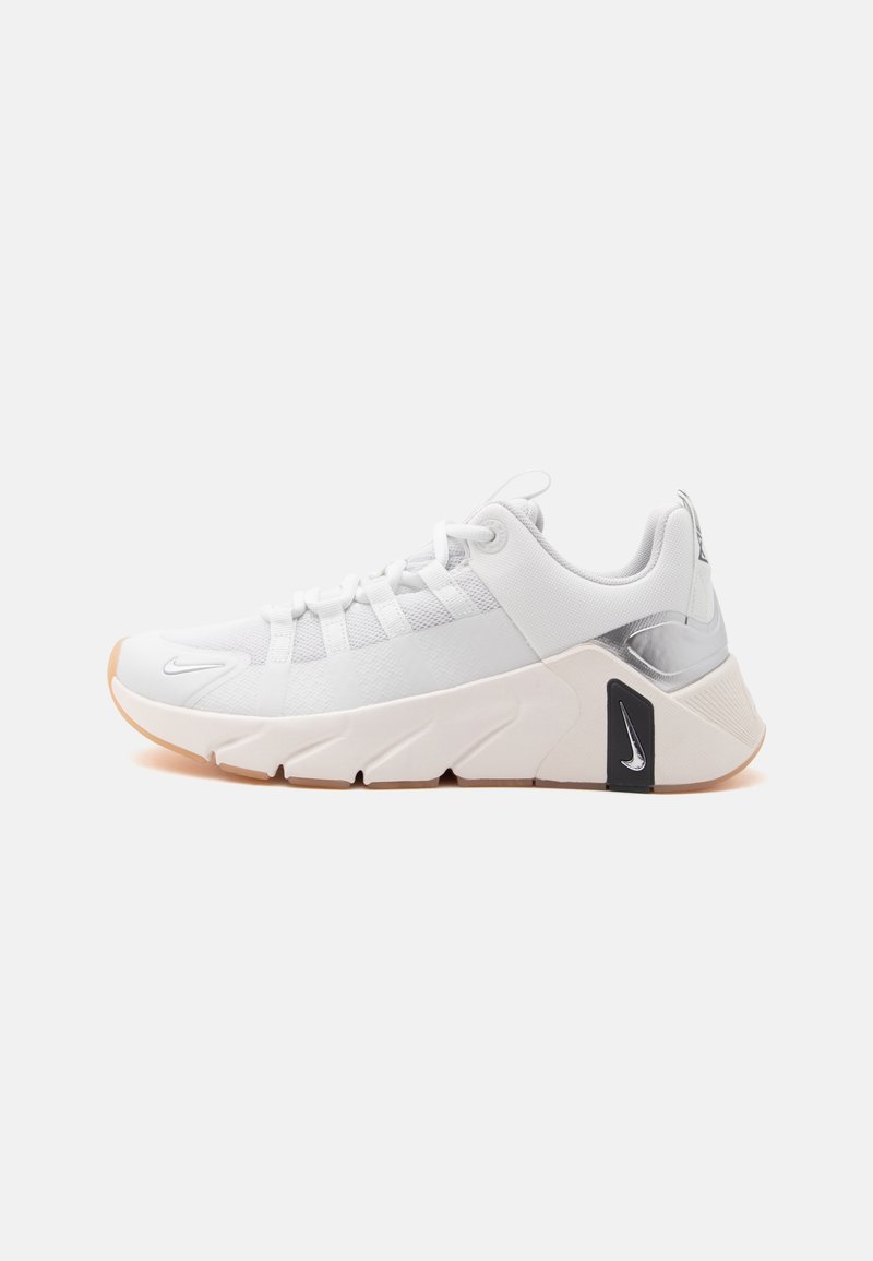 Λευκό αθλητικό παπούτσι Nike με παχιά σόλα, ασημί λεπτομέρεια στη φτέρνα και μικρά μαύρα και ασημί λογότυπα Nike στη σόλα και στη μύτη.