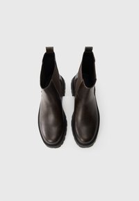 Rudos odinės Chelsea botai su glotniu paviršiumi, elastingais šonų intarpais ir masyviu juodu guminio pado. Yra kilpa, skirta lengvam užsivilkimo.