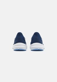 Un paio di scarpe da ginnastica blu navy con suole bianche viste da dietro su uno sfondo bianco uniforme.