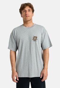 Gray short-sleeve t-shirt made of cotton, featuring a small black and orange floral design on the left chest with "Billabong" text.