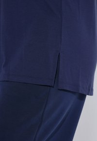 Navyblauwe korte mouwen shirt met een rechte zoom en zijsplitten. Gemaakt van zachte katoenstof met een gladde textuur.