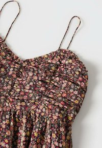 Robe fleurie avec des couleurs rose, jaune et noir, dotée de fines bretelles spaghetti et de détails froncés sur le buste et la taille.