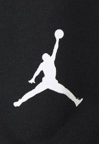 Tessuto nero con una grande silhouette bianca di una figura in salto che tiene un pallone da basket, con una texture liscia e elementi di design minimi.