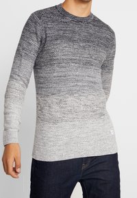 Stickad tröja med gradientdesign som övergår från mörkgrå till ljusgrå. Har rund halsringning och ribbade muddar och nederkant.