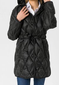 Sort quilted pufferjakke med hætte, med en bælte i taljen, trykknapper og en blank finish. Designet inkluderer diamantformede mønstre.