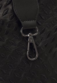 Schwarze Lederhandtasche mit einem strukturierten Muster aus Rautenformen, ausgestattet mit einem silbernen Metallschnapphaken und einem glatten Ledertrageriemen.