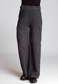 Weite Cargo-Hosen aus strukturiertem, dunklem grauen Cord mit hohem, elastischem Bund und Seitentaschen. Klobige schwarze Schuhe vervollständigen den Look.