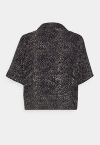 Camicia nera a maniche corte con motivo a pois beige. Presenta un colletto e una vestibilità rilassata e corta. Texture liscia in tutto il capo.