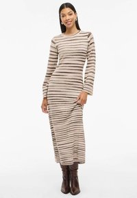 Stripet langermet strikket kjole i beige og brun, med en tettsittende silhuett og myk tekstur, kombinert med brune knee-high støvler.