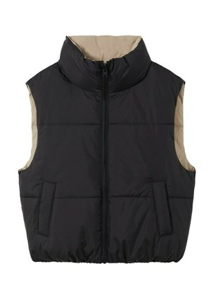 Donna indossa un maglione corto beige, pantaloni beige a vita alta e gamba larga con grandi polsini, gilet imbottito e stivali bianchi con plateau e lacci.