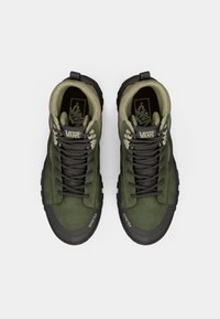 High-top Vans sneakers in dark green suede with a textured light green collar. Features include black laces, rubber outsole, and Gore-Tex branding.