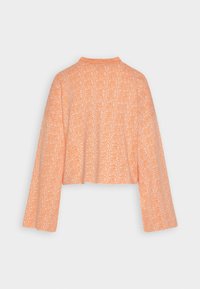 Textured, cropped sweater in light orange with long sleeves and a high collar; features a subtle woven pattern throughout.