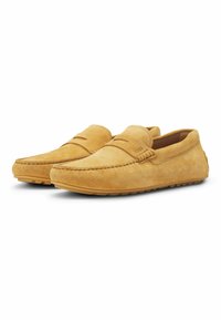 Gule ruskind loafers med et syet design, flad gummisål og slip-on stil med minimal detaljering på overdelen.