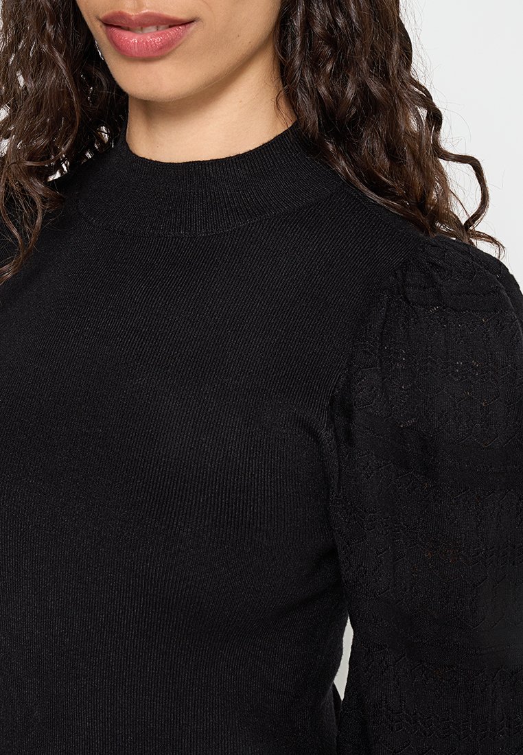 Pull noir avec un col montant, texture côtelée sur le corps et des détails en dentelle complexe sur les manches bouffantes.