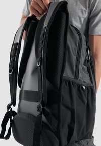 Mochila negra con correas acolchadas, panel trasero texturizado, cierres con cremallera y múltiples compartimentos. Tela duradera y diseño resistente al agua.