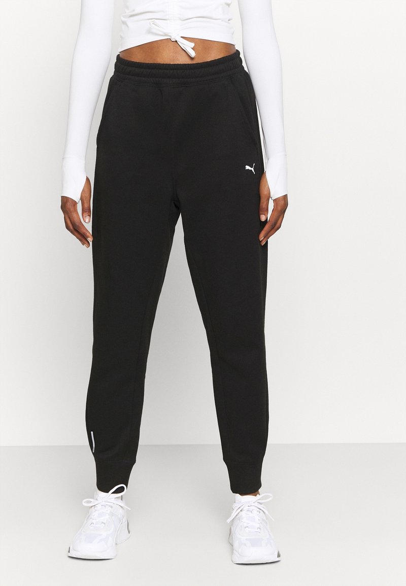 Zwarte sweatpants van zacht materiaal met een elastische tailleband, taps toelopende benen en een klein wit logo op de linker bovenbeen.