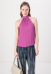 Fuchsiový halter top s naťahovacím výstrihom; ľahká, hladká látka. V kombinácii s džínsami so metalickými vertikálnymi pruhmi a vreckami.