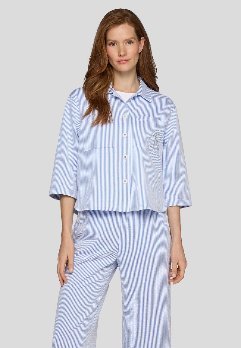 Gemustertes, hellblaues und weißes Pyjama-Set aus weichem Stoff; umfasst ein knöpfbares Hemd mit zwei vorderen Taschen und lockerer Passform.