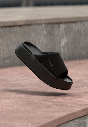 Infradito neri con una larga fascia superiore, realizzati in materiale liscio simile alla gomma. Presentano una suola texturizzata e un logo discreto sulla fascia.