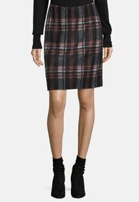 Rutiga kjolen i svart, vinröd och grå; knälång stickad med elastisk midja; matchad med svarta ankelstövlar.