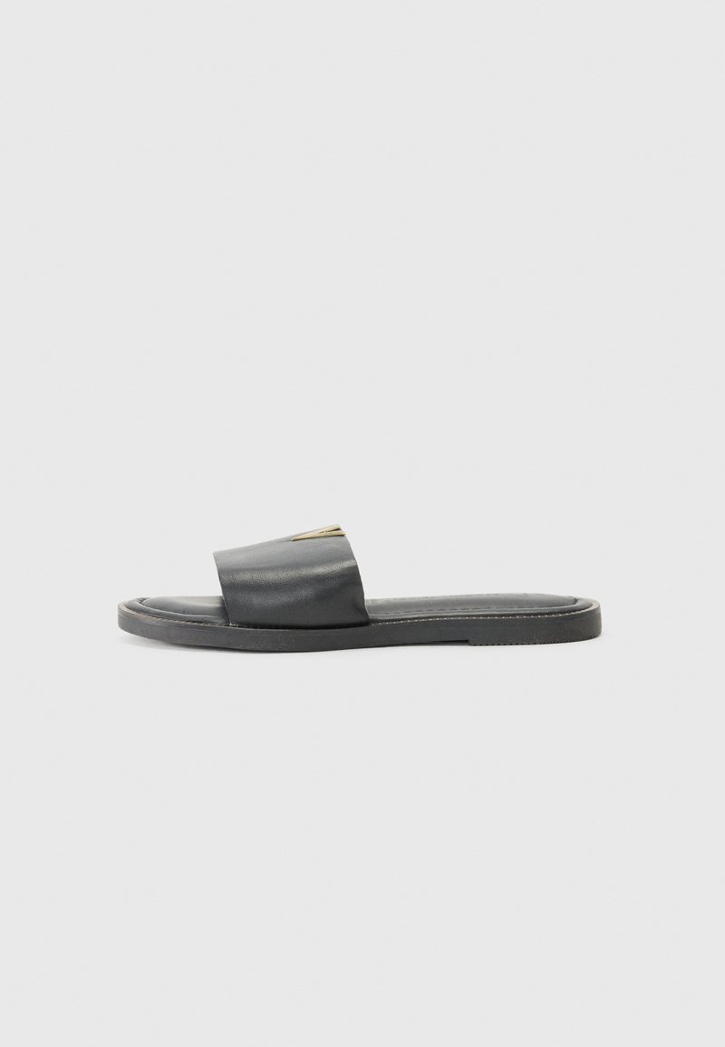 Sandal noir à glissière avec une large sangle et un design minimal, dotée d'un dessus en cuir lisse et d'une semelle plate avec des coutures contrastées.