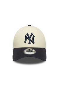 Boné de basebol ajustável com copa de cor creme, pala azul-marinho e logótipo bordado do New York Yankees em azul-marinho na parte frontal.