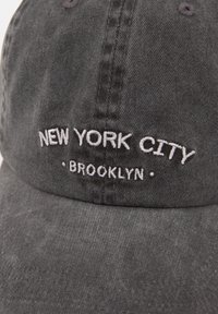 Fekete pamut sapka, amelyen hímzett "NEW YORK CITY" és "BROOKLYN" felirat található. Puha tapintású, ívelt hajtókával és látható varrásmintával.