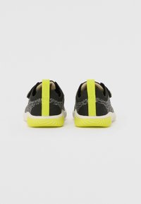 Le sneakers in maglia nere presentano un design texture, dettagli in neon giallo e una suola bianca. La parte posteriore include distintivi ganci per una facile calzata.