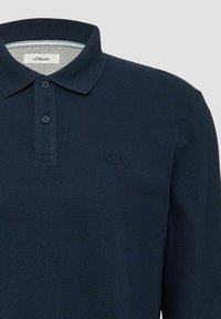 Marineblauwe polo met lange mouwen van textuurstof, voorzien van een drie-knopenlijst en een subtiel geborduurd logo op de borst.