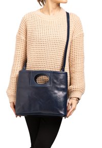 Borsa a tracolla in pelle blu navy con forma rettangolare e manico ad arco circolare, caratterizzata da una superficie liscia e tracolla regolabile.