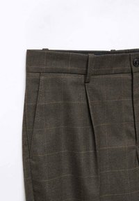 Pantalon sur mesure à carreaux marron foncé avec poches latérales, passants pour ceinture et fermeture par bouton à la taille.