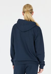 Sudadera de color azul marino oscuro con un corte relajado, tela suave, bolsillo canguro y capucha ajustable con cordones. Presenta puños y dobladillo acanalados.