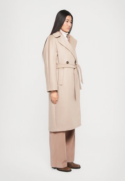 Light beige long coat in a wool blend, featuring a double-breasted design, large collar, and belted waist. Soft texture with minimal detailing.