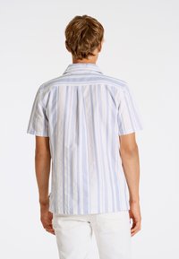 Camicia a maniche corte, con colletto, di colore bianco con strisce verticali blu, caratterizzata da un orlo dritto e un sottile dettaglio a piega sul retro.