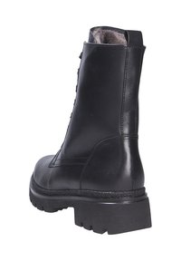 Bottine noire en cuir avec une surface texturée, détail de fermeture éclair arrière et semelle en caoutchouc épaisse. Présente un léger talon surélevé et un col rembourré.