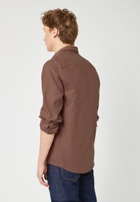 Camicia a quadri marrone con vestibilità rilassata, colletto a bottoni, maniche arrotolate e leggera curvatura dell'orlo. Realizzata in tessuto testurizzato.